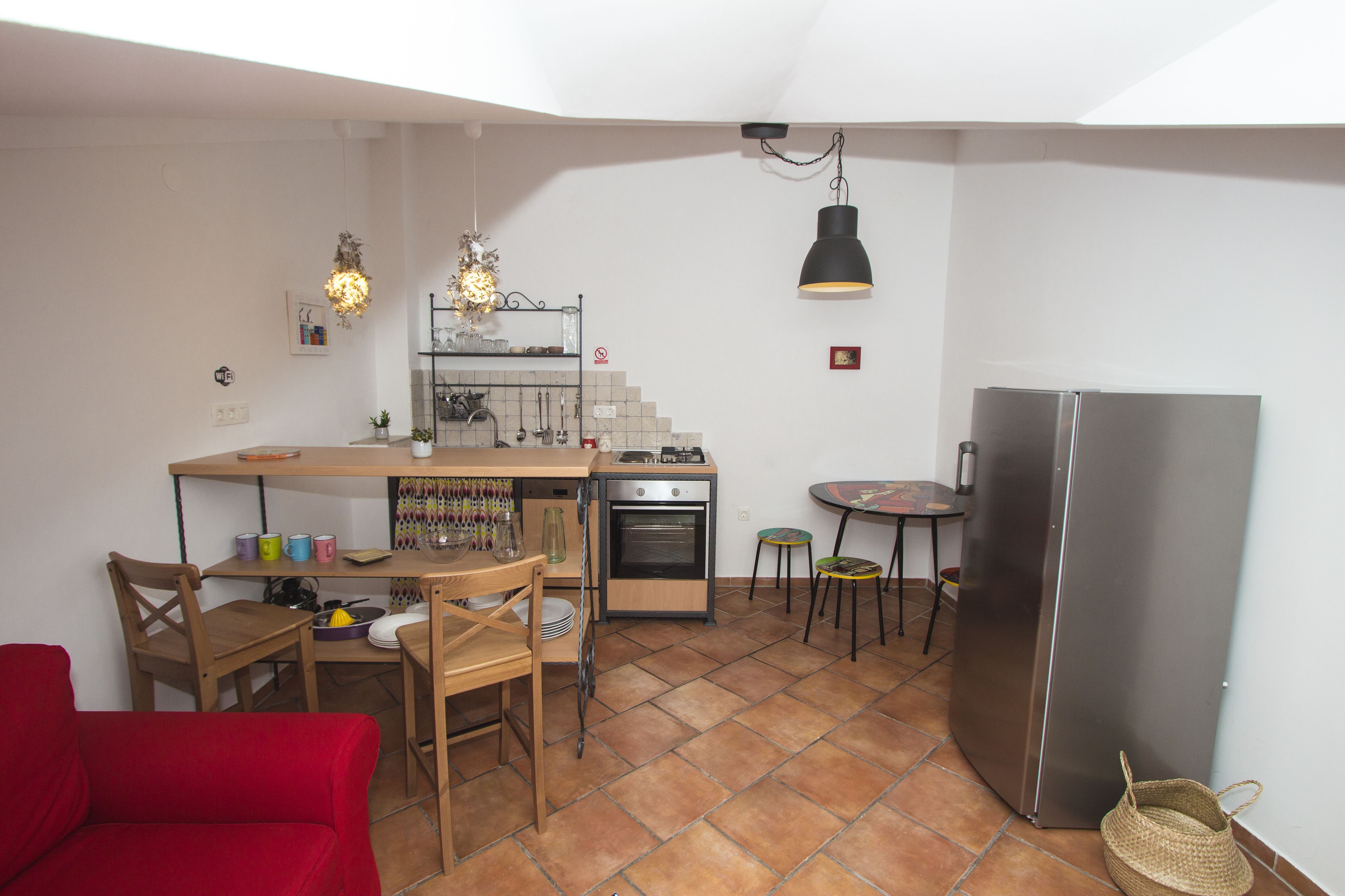 Une cuisine compacte avec un coin repas, une chaise rouge, une petite table et un réfrigérateur.