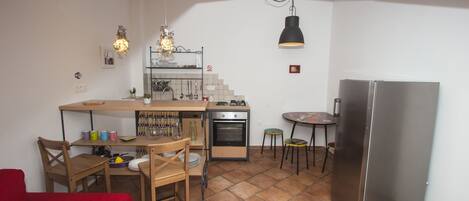 Une cuisine compacte avec un coin repas, une chaise rouge, une petite table et un réfrigérateur.