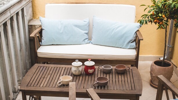 A cozy outdoor seating area with a sofa and wooden chairs, a small table with cups and a teapot, and a potted plant. - Jerry & Oli Apartments (Sibenik)