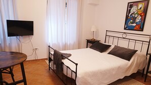 A bedroom with a bed, a TV, a table, and a painting on the wall. - Jerry & Oli Apartments (Sibenik)