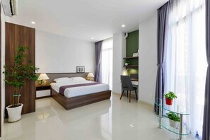 Relax in a serene space with a large bed, glass desk, and potted plants.