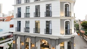Et hotel med flere etager, en hvid facade, balkoner og en godt oplyst indgang.