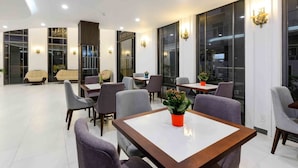 En moderne hotellobby med flere siddeområder, store vinduer og dekorative væglamper.