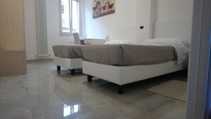 Un dormitorio moderno con una cama grande, una silla pequeña, un escritorio y un radiador.