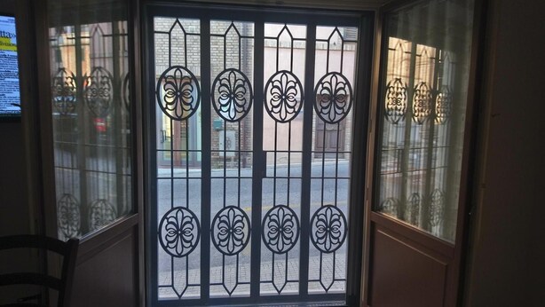 Una ventana con rejas decorativas de hierro y vista a la calle.
