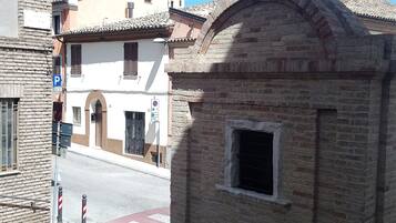 A street view with a building featuring a small window and a brick facade.
