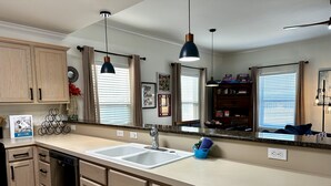 Una cocina moderna con una isla grande, electrodomésticos de acero inoxidable e iluminación colgante.