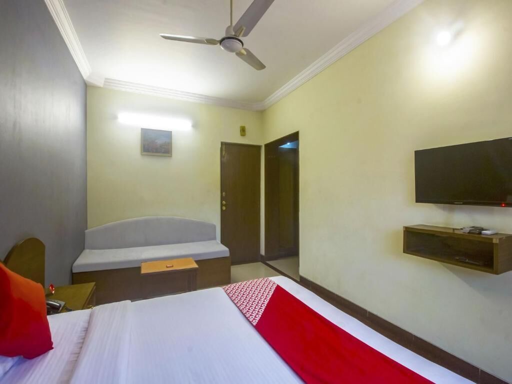 A hotel room with a bed, a desk, a chair, a television, and a ceiling fan.