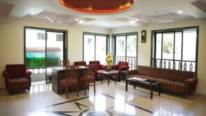 A spacious lobby with a central coffee table, seating area, and large windows offering a view of the outdoors. - Basilica Holiday Home (Mawal)