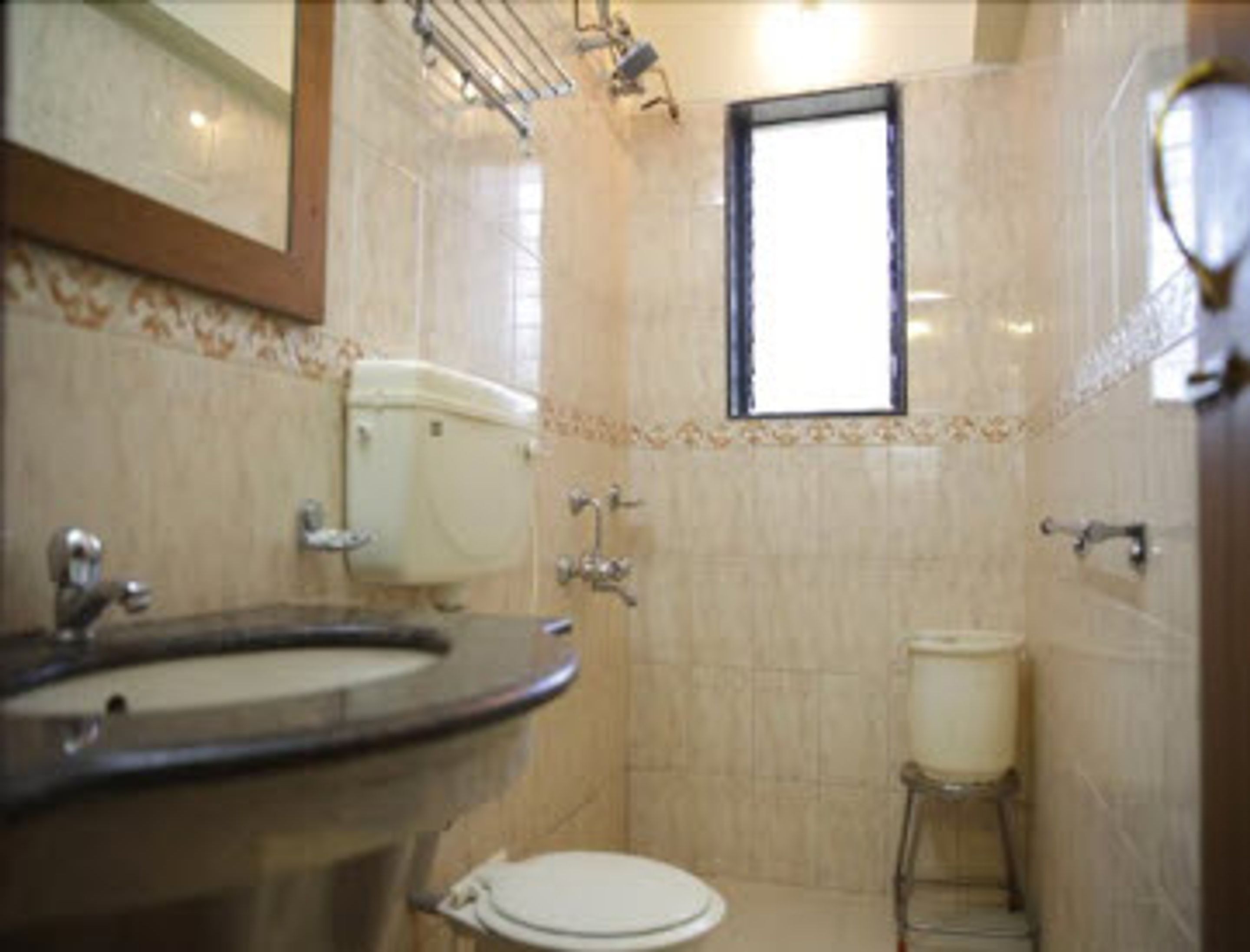 A bathroom with a toilet, sink, and mirror.