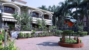 A hotel courtyard with a central circular paved area, surrounded by lush greenery and palm trees. - Basilica Holiday Home (Mawal)