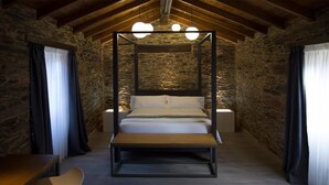 A four-poster bed in a rustic stone-walled room with a wooden ceiling and a bench at the foot of the bed. - Lar de Donas (Meira)