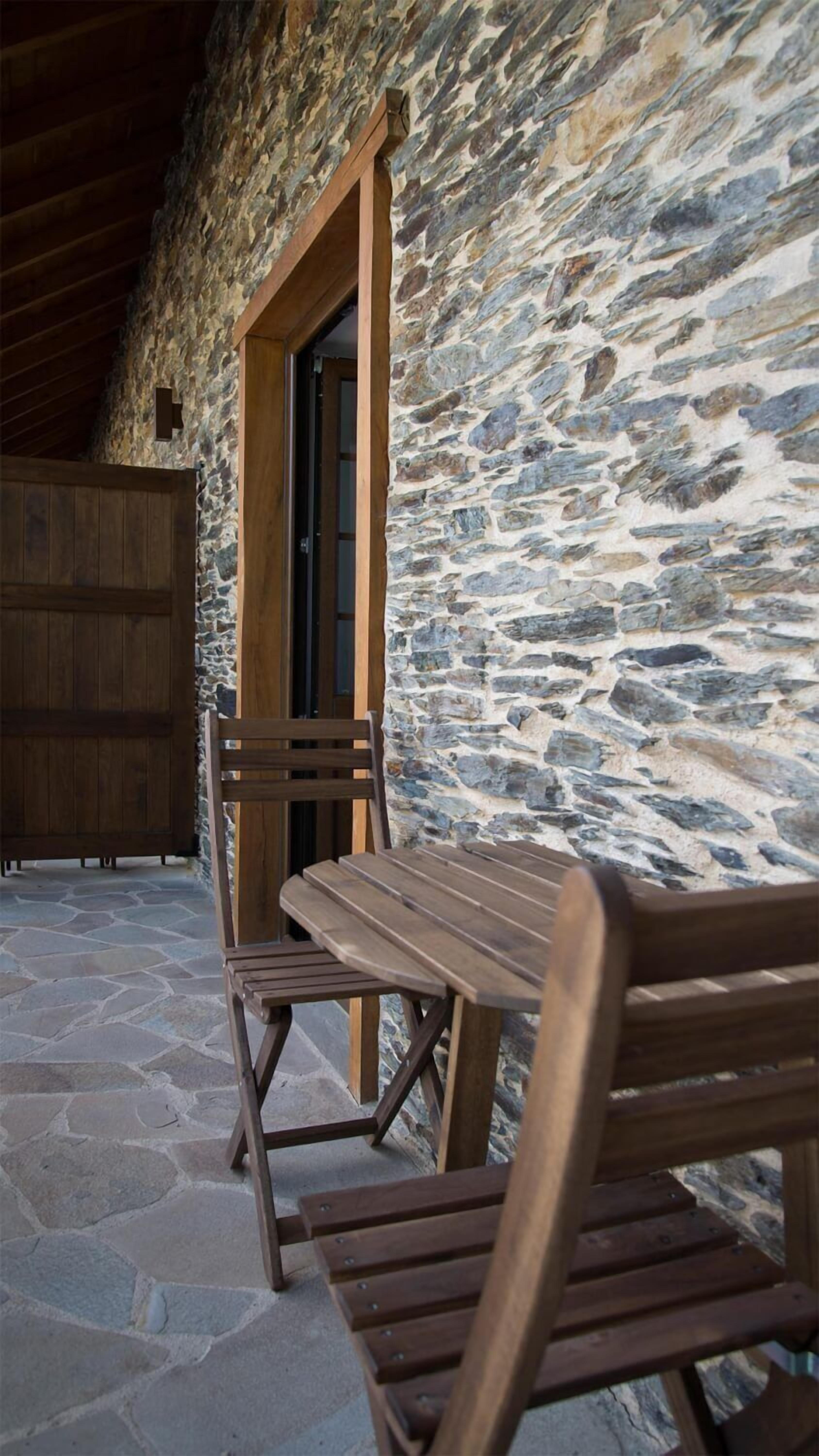 A stone wall with a wooden bench and a door.