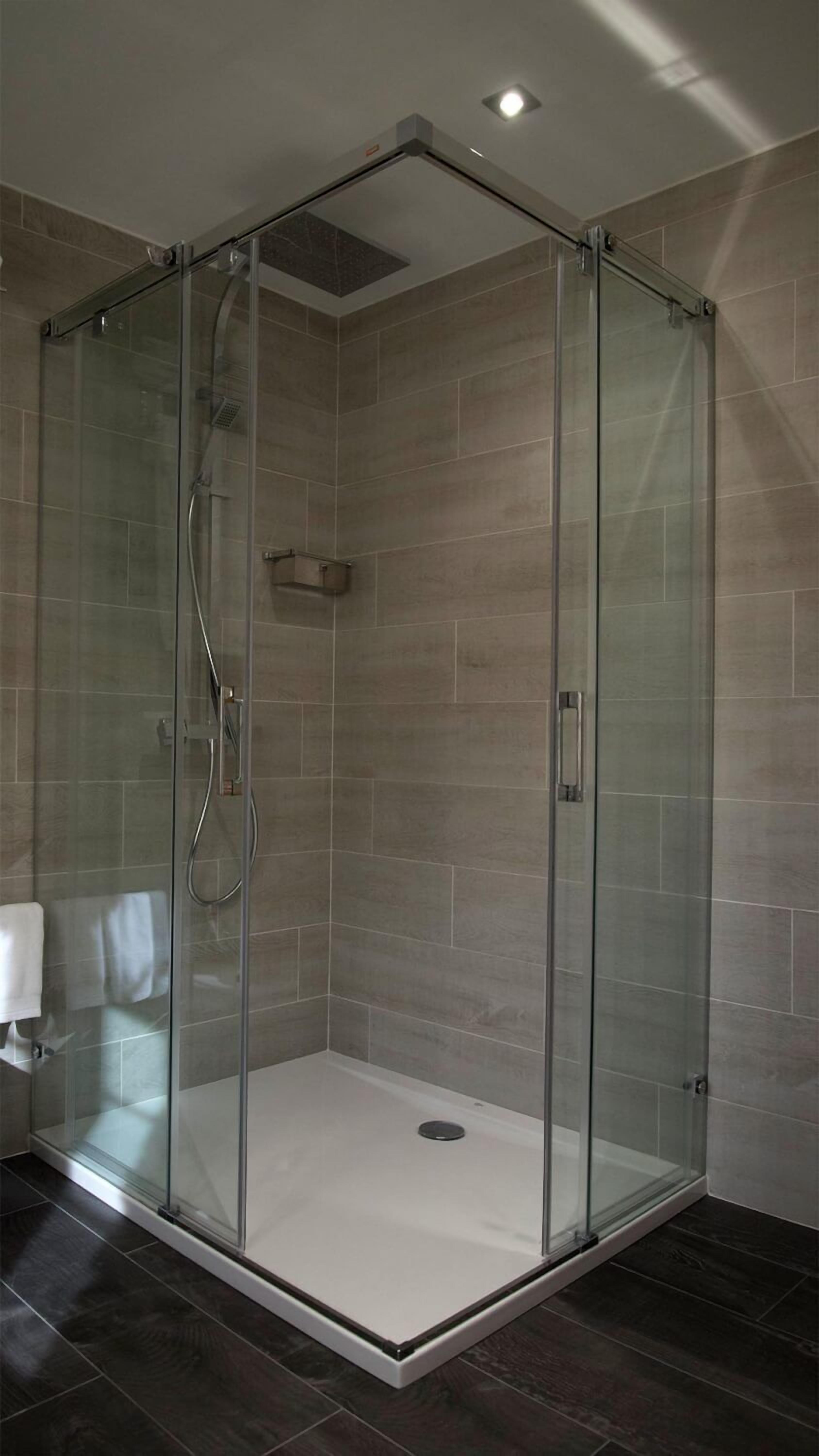 Une douche à l’italienne entièrementClose avec des parois en verre, un sol carrelé et un éclairage encastré au plafond.