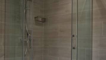 Une douche à l’italienne entièrementClose avec des parois en verre, un sol carrelé et un éclairage encastré au plafond.