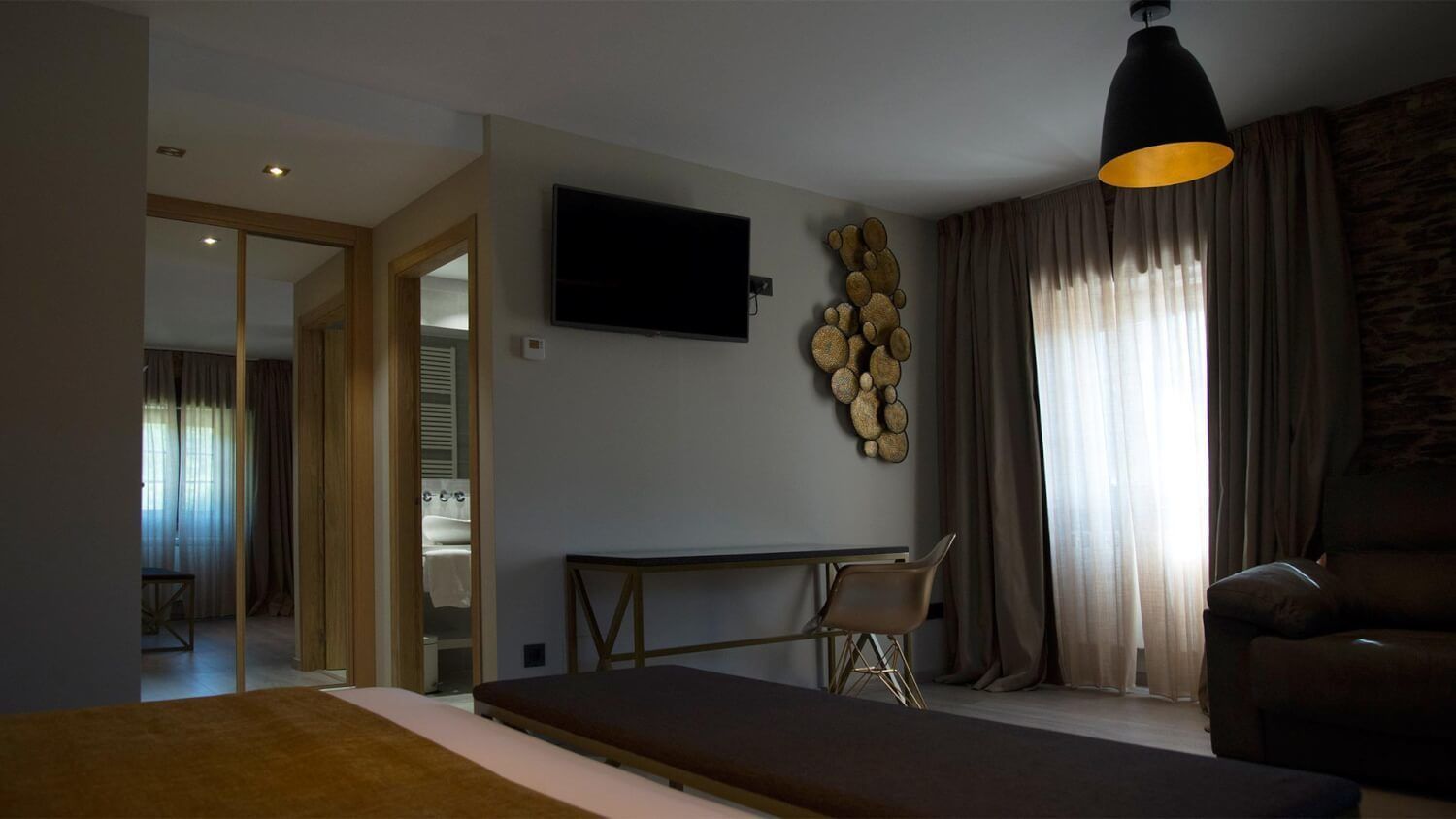 A modern bedroom with a bed, a desk, a chair, a television, and a unique wall decoration.