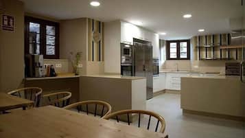 A modern kitchen with a central island, built-in appliances, and a dining area with wooden chairs.