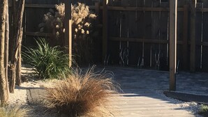 A wooden pergola structure with a gravel pathway leading to it.