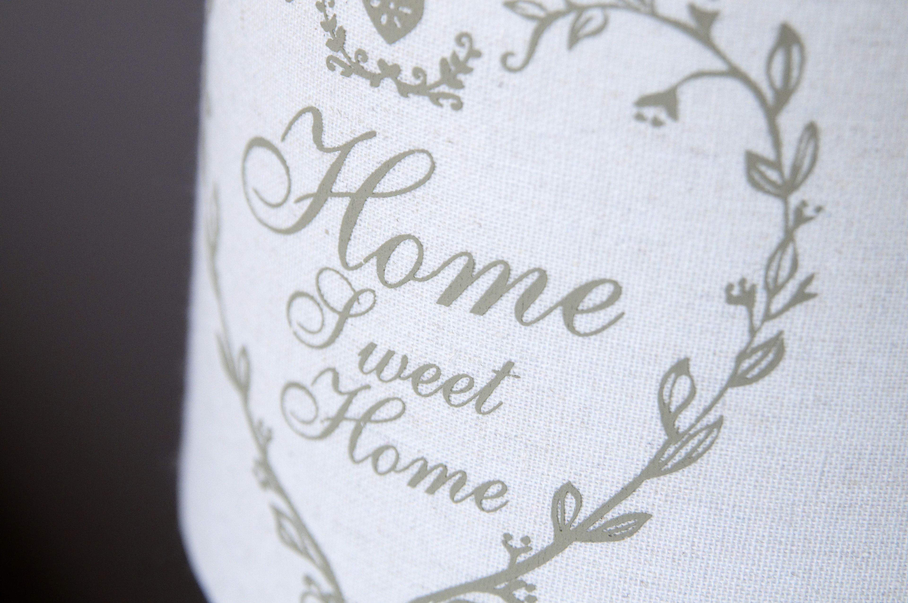 Primer plano de un tejido con la frase 'Home Sweet Home' bordada en una caligrafía decorativa.
