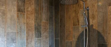 A shower area with wooden paneling and a metal showerhead.