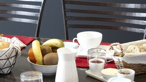A breakfast table set with various dishes, including fruits, bread, and beverages.