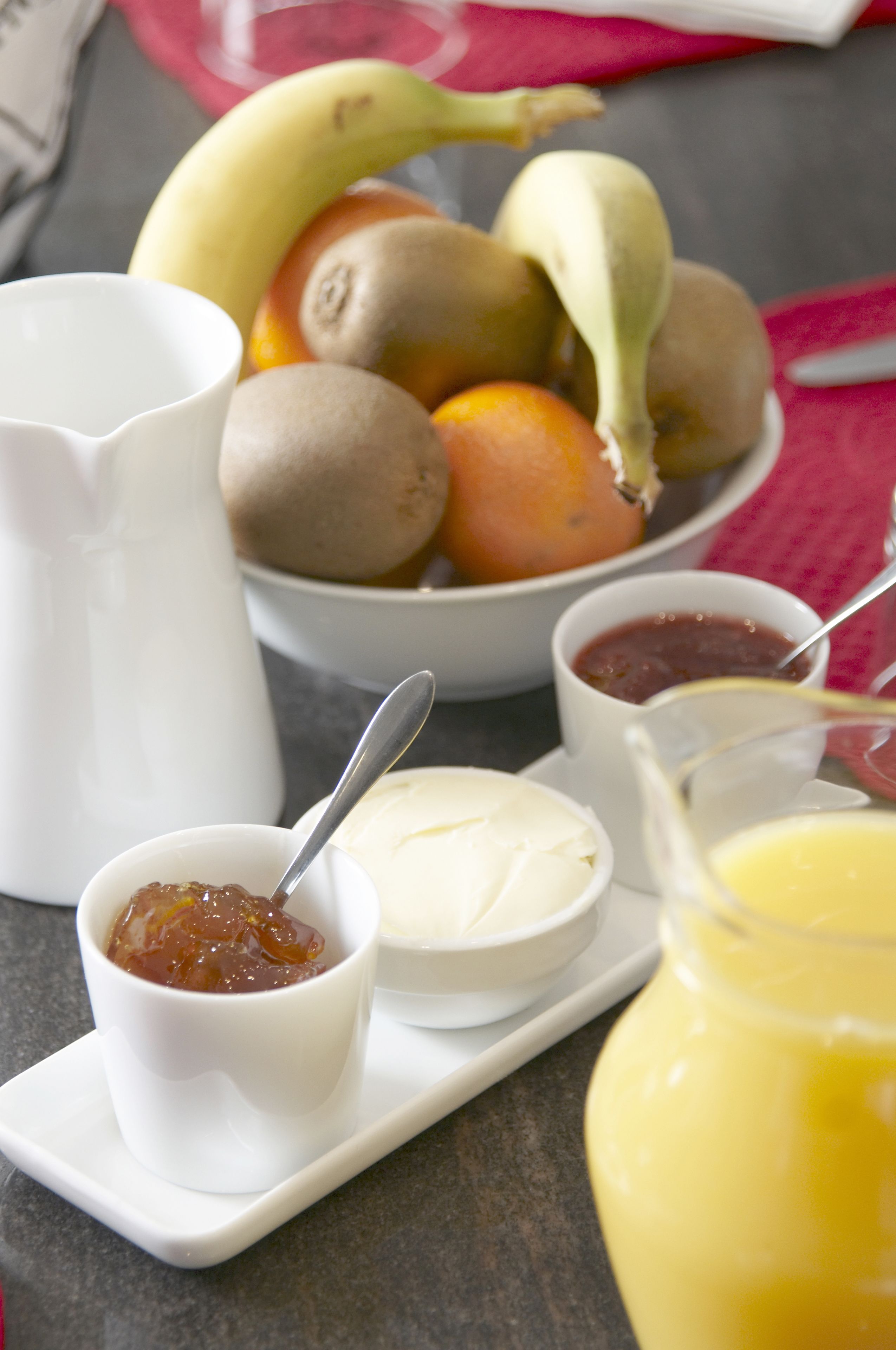 A breakfast setting with a bowl of fruit, a pitcher, and small bowls of condiments.