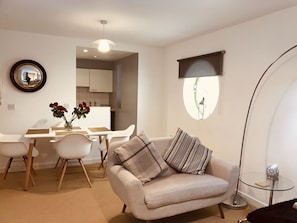 Relax in this stylish living room with a comfortable sofa, dining area, and large window.