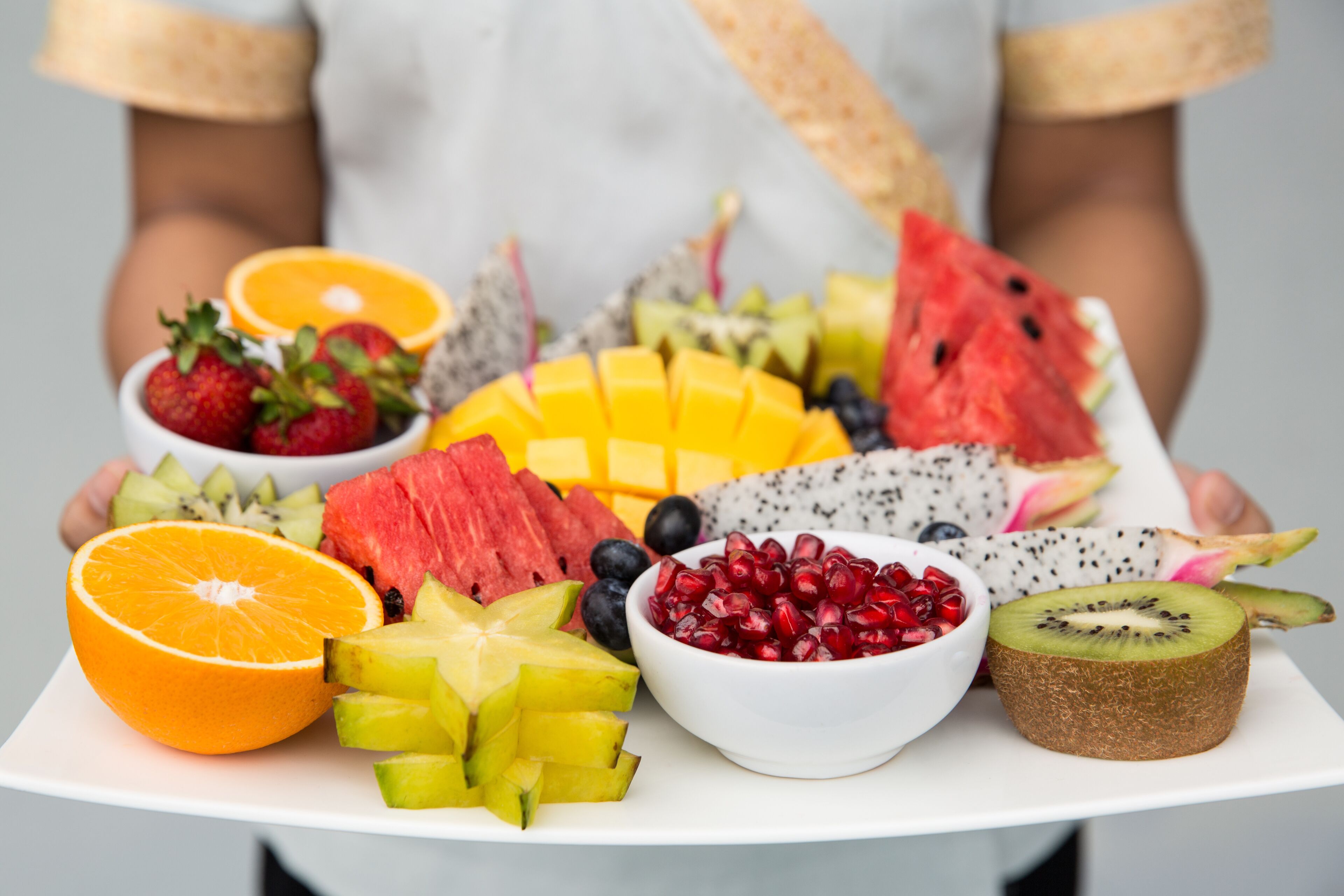 En bakke med et udvalg af frugter, heriblandt jordbær, vandmelon, kiwi, mango, granatæble og dragefrugt.