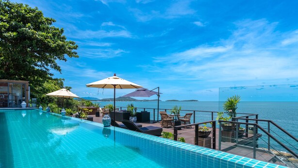 A pool area with lounge chairs and umbrellas, overlooking a body of water.