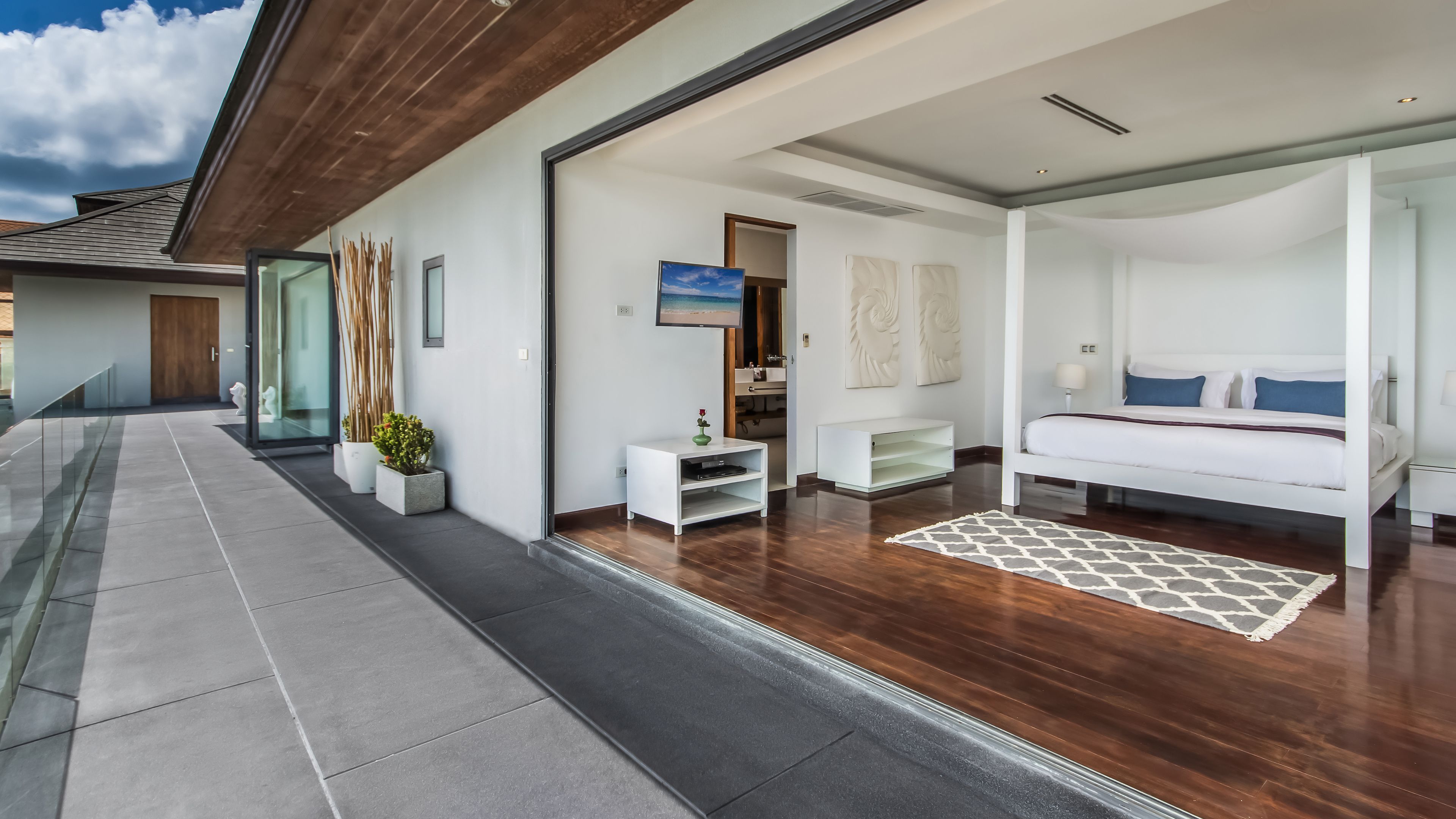 A modern hotel room with a large bed, a TV, and a small seating area.
