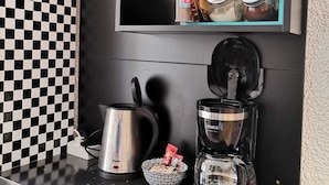 A kitchen counter with a coffee maker, a kettle, and jars of condiments. - Apartment Toma (Sibenik)