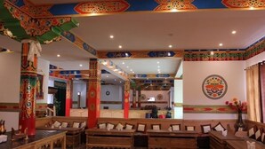 Una posada tradicional con bancos y mesas de madera, decoraciones coloridas en las paredes y un pilar central.
