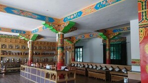 Habitación tradicional con muebles de madera, una mesa central y decoraciones de pared coloridas.