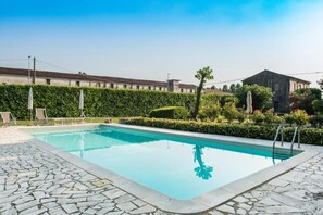 A rectangular swimming pool with stone tiles, surrounded by a hedge and a row of chairs. - Azienda Agricola Le Colombare (Nogarole Rocca)