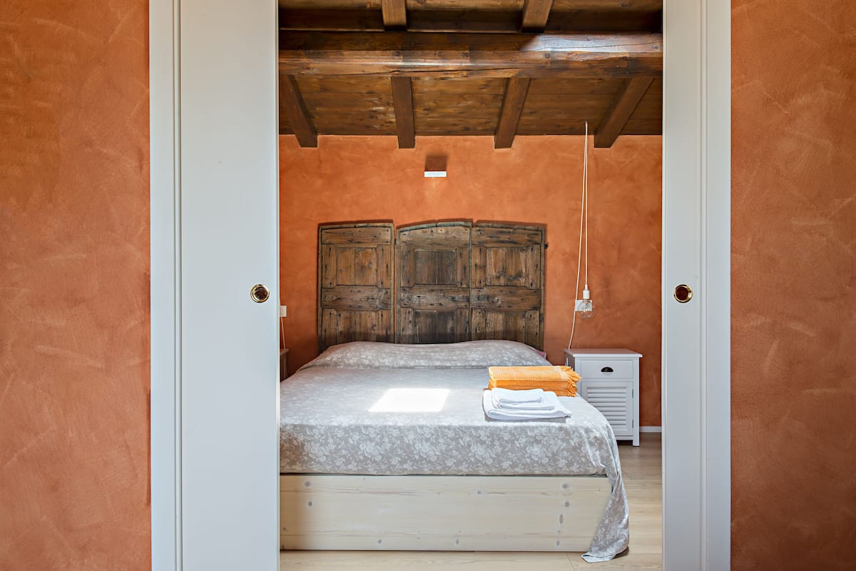 Un dormitorio con cabecera de madera, cama con colcha estampada y mesitas de noche.