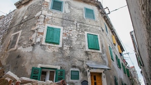 A historic building with multiple windows and a door, featuring traditional shutters and a visible brick facade.