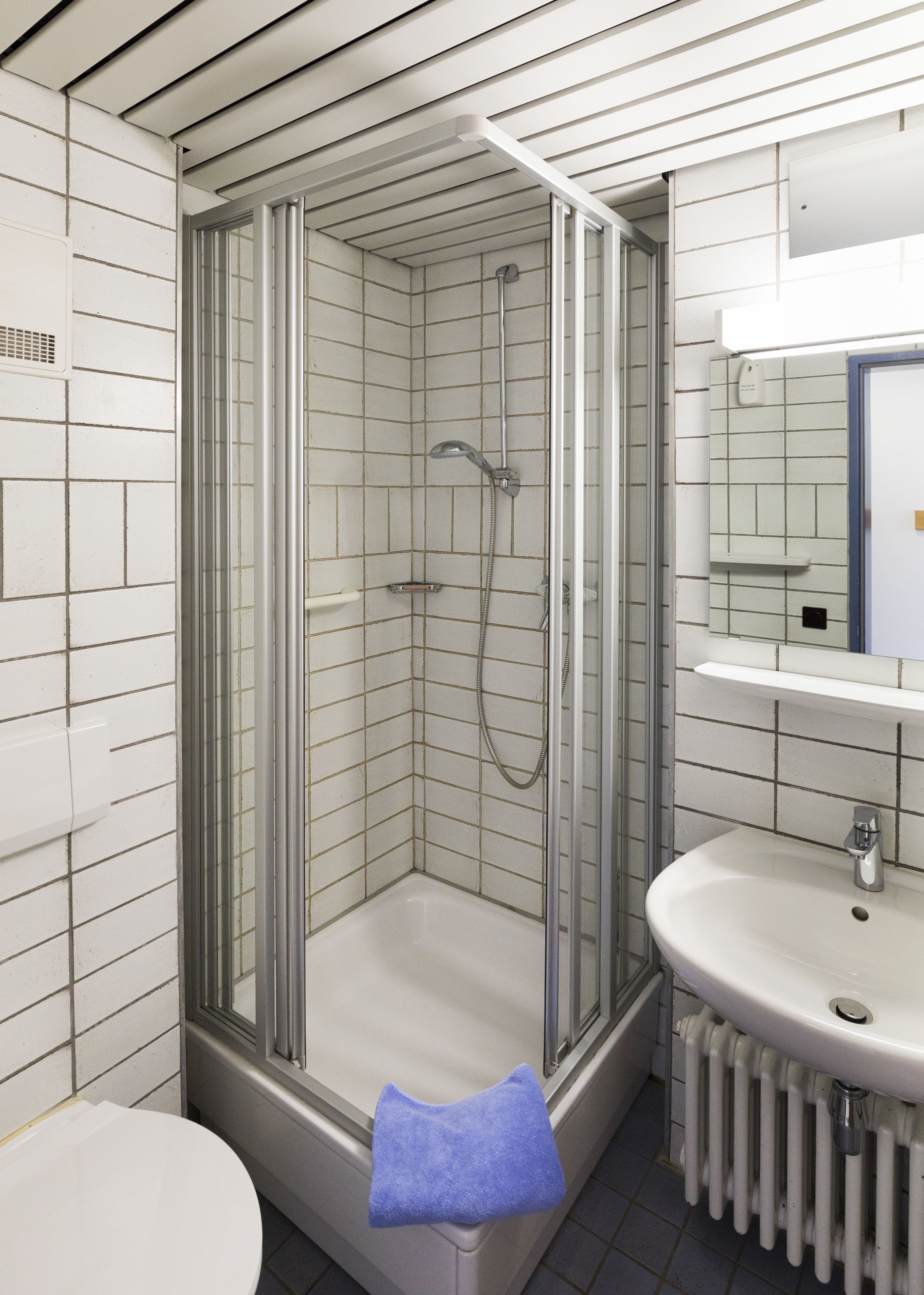 Ein modernes Badezimmer mit einer Duschkabine, einem weißen Waschbecken und einer Toilette.