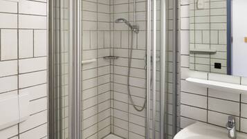 Ein modernes Badezimmer mit einer Duschkabine, einem weißen Waschbecken und einer Toilette.