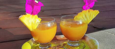 Two glasses of orange beverage with pineapple garnish on a tray.