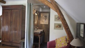 Una habitación con techo de madera, un sillón rojo, una mesa y un armario.