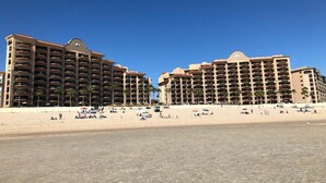 Un hotel sulla spiaggia con numerosi balconi, una spiaggia sabbiosa e cieli sereni.