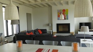 Ein modernes Wohnzimmer mit Sofa, Fernseher und Essbereich.