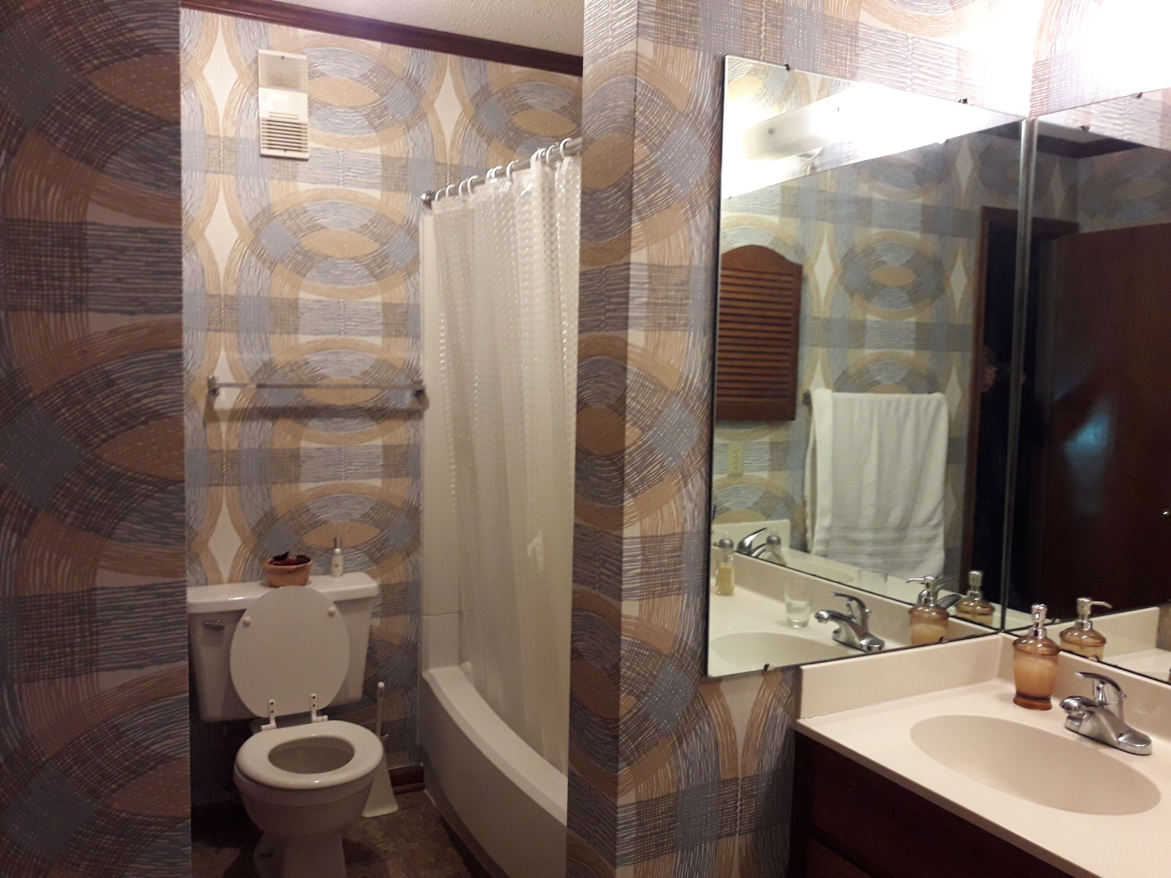 A bathroom with a toilet, shower, and sink.