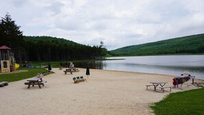 A lakeside campsite with picnic tables, a playground, and a large rock in the foreground. - Perfect For Large Families & Groups - Excellent Location (Snowshoe)
