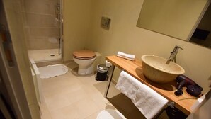Un bany amb dutxa, vàter, rentamig i penjador de tovalloles.