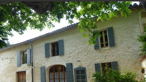 A rustic stone building with a symmetrical facade, featuring a central arched doorway, shuttered windows, and a gravel driveway. - Le rêve d'Emma Chambres d'hôtes (Plan-d'Orgon)