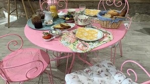 A round table with pink metal chairs, set with breakfast items like toast, fruit, and a jug of orange juice. - Le rêve d'Emma Chambres d'hôtes (Plan-d'Orgon)