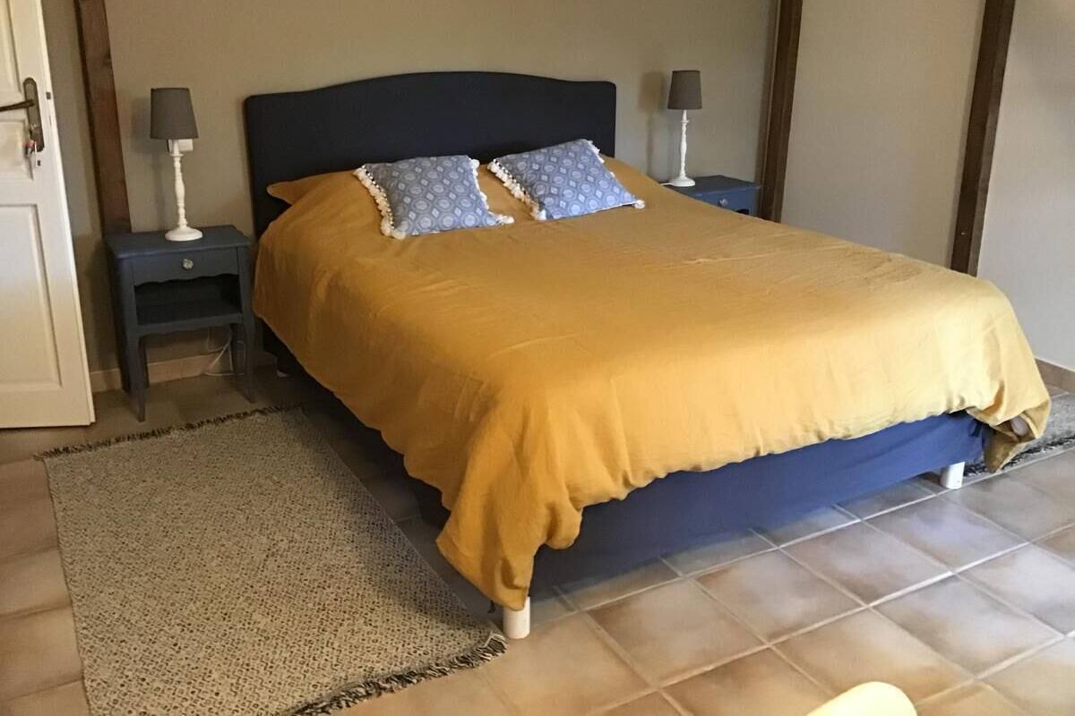A bedroom with a bed, two bedside tables, and a rug.