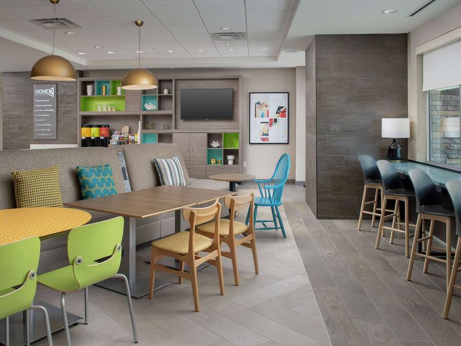 Eine moderne Hotelhalle mit Essbereich, Bar und einem großen Bildschirm.