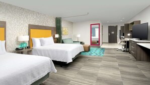 A hotel room with two beds, a desk, a television, and a bathroom visible through a door. - Home2 Suites by Hilton Phoenix Airport South (Phoenix)
